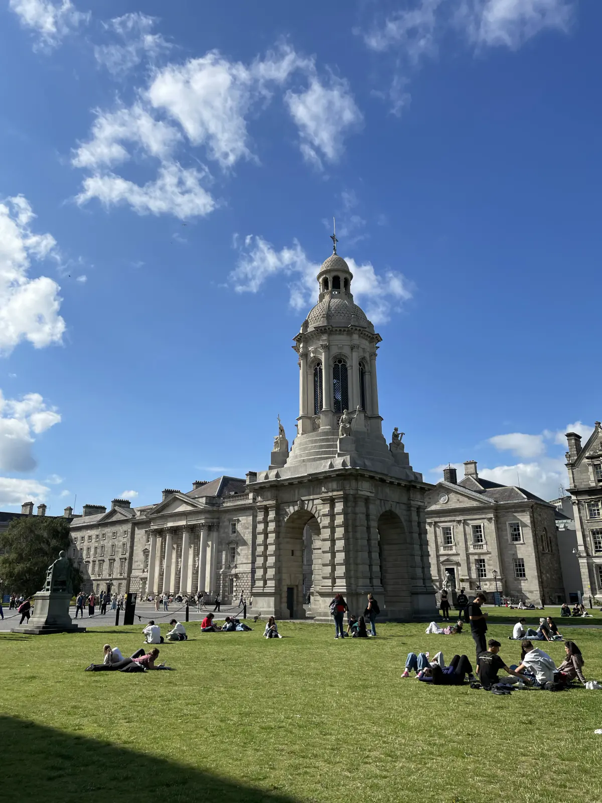 Historic stone buildings and a domed bell tower beneath a bright blue sky.